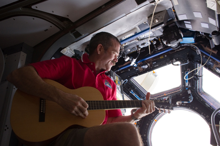 Strumming on a guitar in the Cupola module.