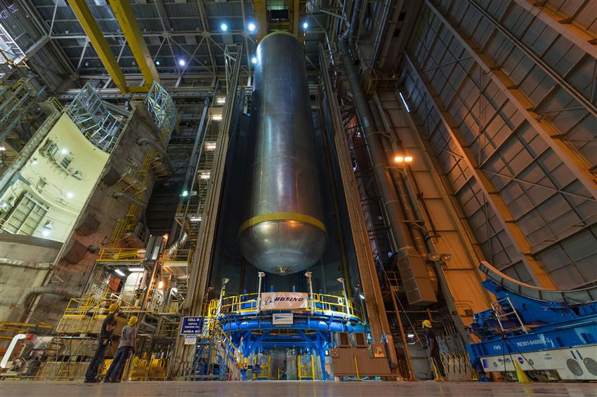 A massive cylindrical liquid hydrogen tank suspended vertically in an assembly facility