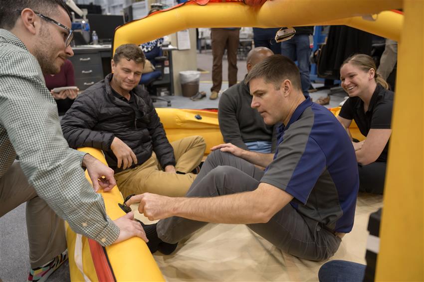 The astronauts and an instructor are in an inflatable boat.