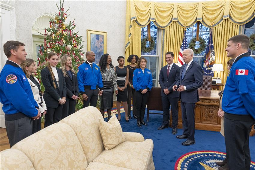 The astronauts in their family members and Joe Biden in the Oval Office.