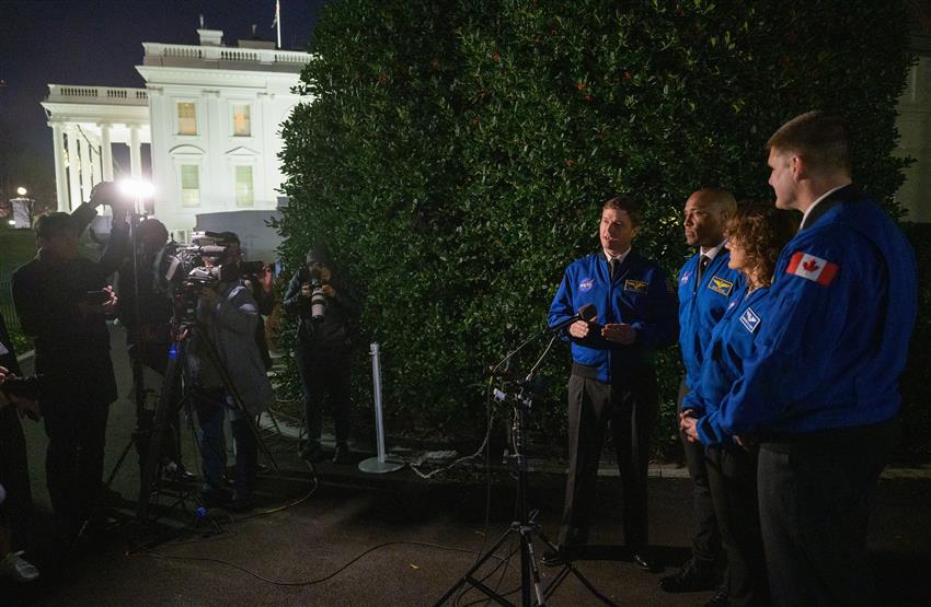 The four astronauts standing near the White House in front of microphones and cameras.