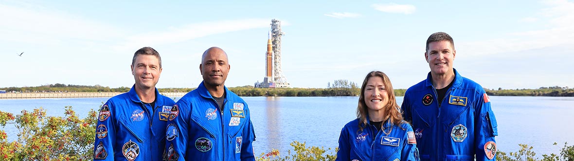 L'équipage d'Artemis II avec la fusée SLS loin derrière.