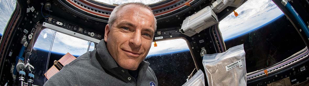 L'Astronaute David Saint-Jacques tient deux sacs Ziploc pleins de graines de tomates.
