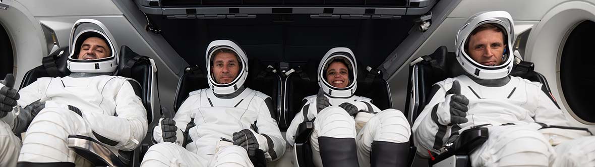 Crew-13 are seated in a mock-up of the Dragon capsule wearing space suits.