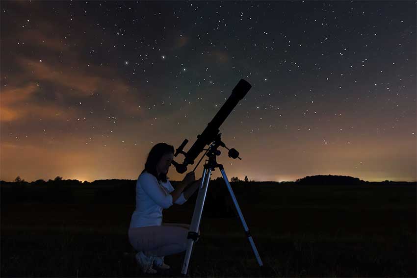 Une femme observe le ciel à l'aide d'un télescope