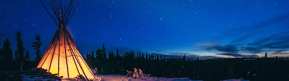 A tipi shines under the starry sky