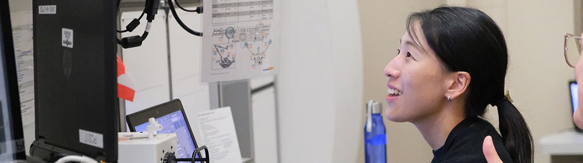 A woman operates a hand controller in front of a laptop and several screens.