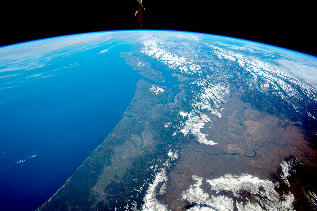 La chaîne montagneuse enneigée des Cascades (en avant-plan), dans le nord-ouest des États-Unis, fait place aux Rocheuses et à la chaîne Cotière au Canada, avec l'île de Vancouver au large. Plusieurs volcans actifs — mont Saint Helens, mont Rainier et mont Hood — parsèment les Cascades dans cette photo prise par un membre d'équipage de la Station spatiale internationale. (Source : NASA.)
