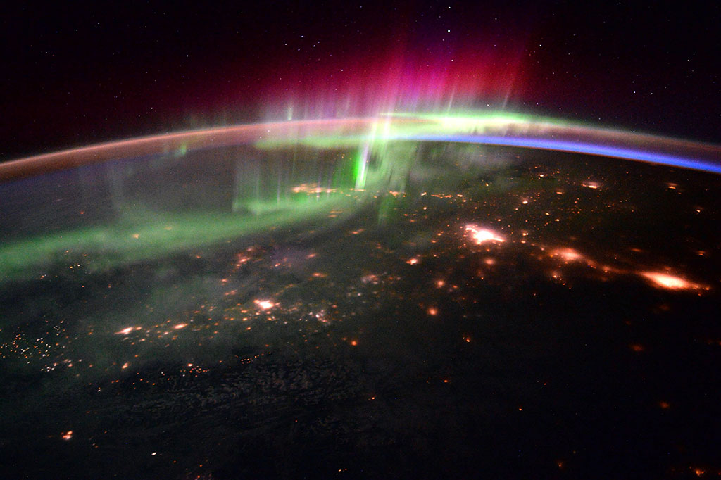 Aurora borealis over Canada captured by European Space Agency astronaut Tim Peake. This view was photographed looking north-east from a point just north of Vancouver; the Canadian Rockies and Banff and Jasper national parks lie in the foreground. The bright patches of light mark the locations of Edmonton, Red Deer and Calgary (from left to right). The most active part of the aurora lies over Fort McMurray, Alberta. (Credit: Tim Peake/European Space Agency)