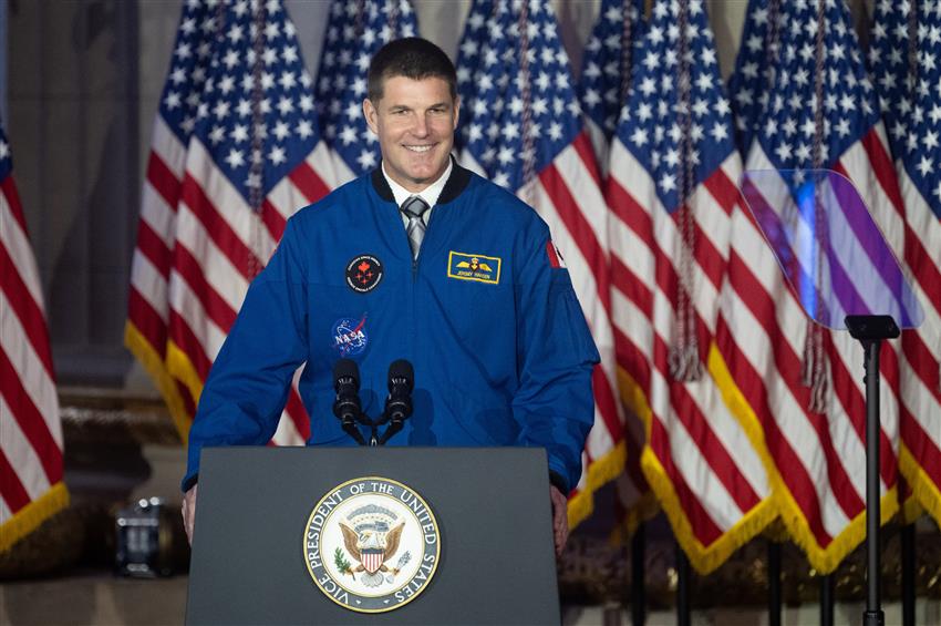 Jeremy wearing his flight jacket stands behind a podium that says Vice President of the United States.