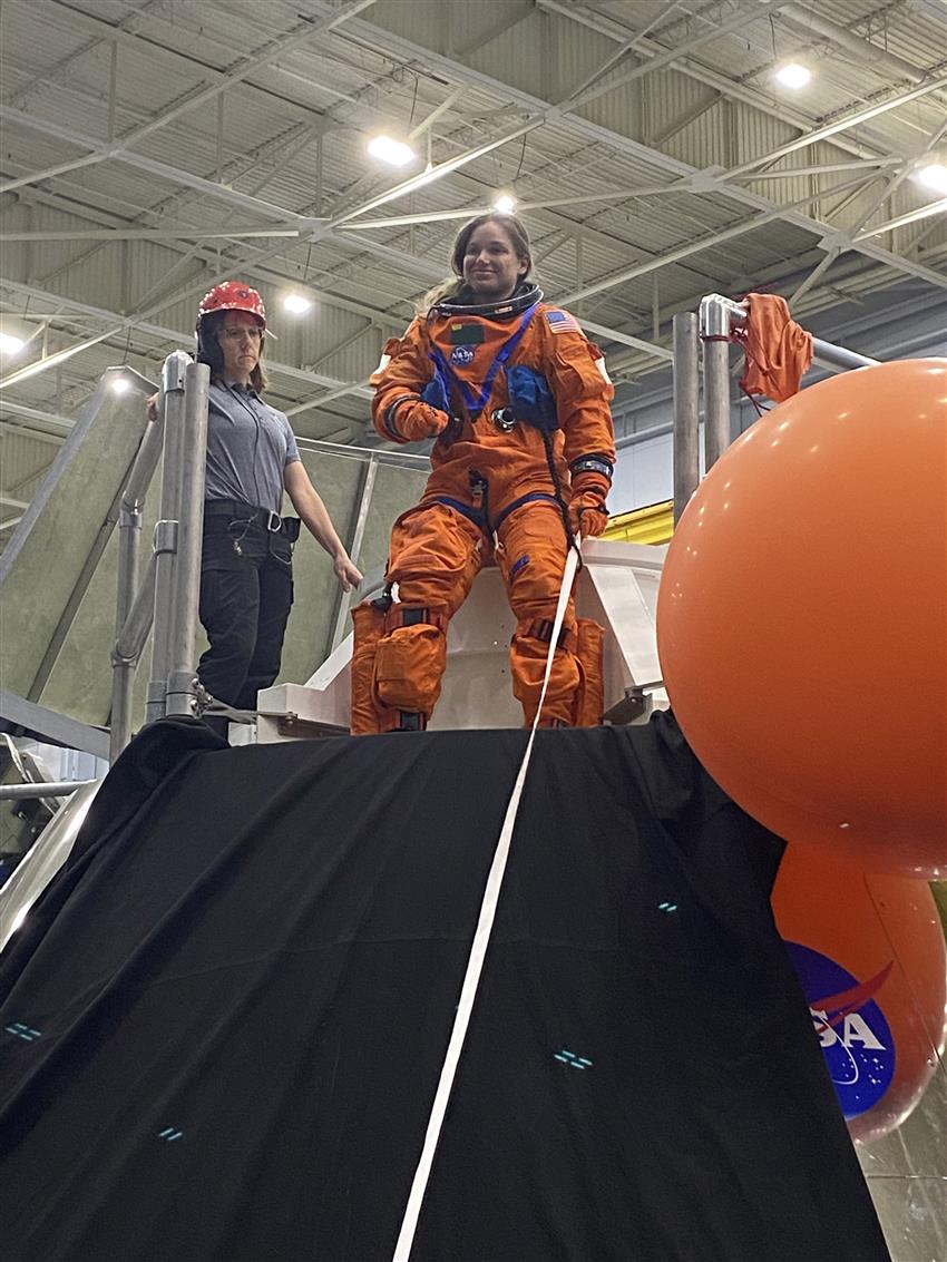 Jenni wears an orange spacesuit during training. 