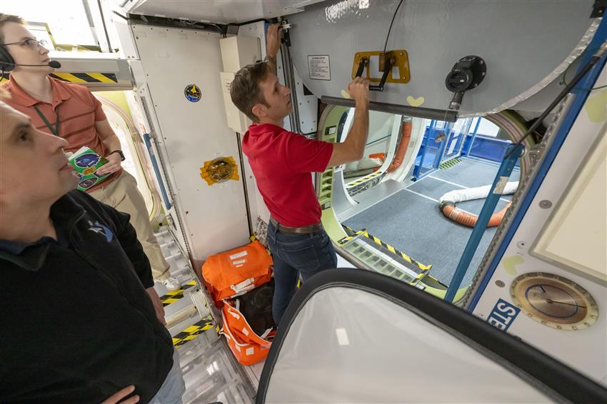 Joshua closes a hatch in a mock-up of the International Space Station. 