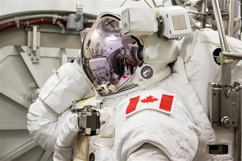 Joshua wears his spacesuit and helmet with the sun visor lowered.