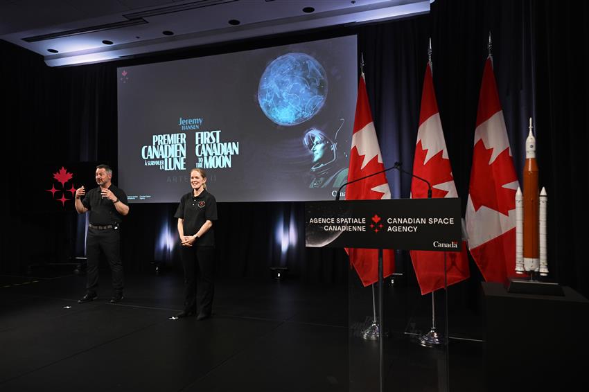 Jamie and Tim stand in front of a big screen.