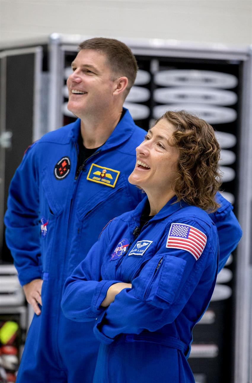 Two astronauts in their blue flight suits, smiling.