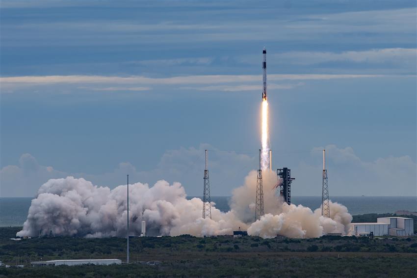 Launch and ascent of the Falcon 9 rocket, accompanied by smoke and flames.