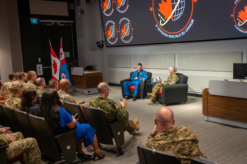 Jeremy stands in front of an audience, some people wearing military uniforms.