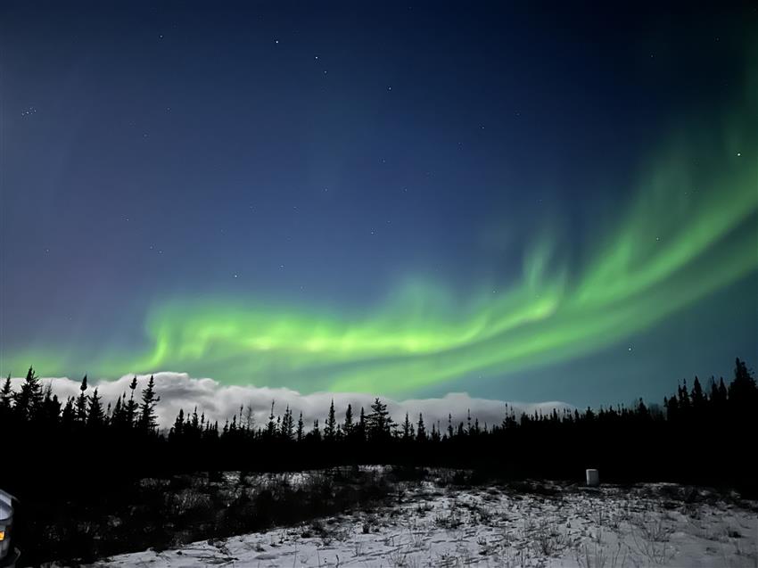 Une aurore boréale verte brille dans le ciel étoilé de Rabbit Lake, en Saskatchewan.