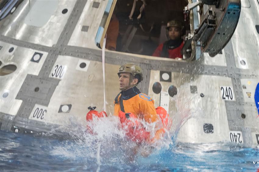 Joshua saute dans une piscine depuis l'écoutille d'une maquette de capsule spatiale. 