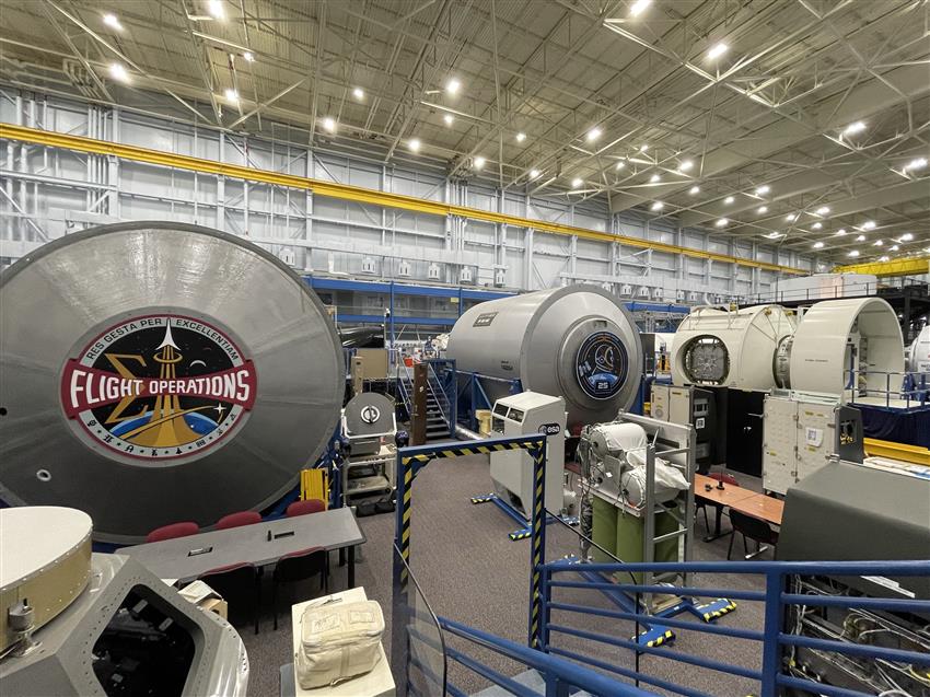 Une très grande pièce avec des modules cylindriques et de l'équipement varié.