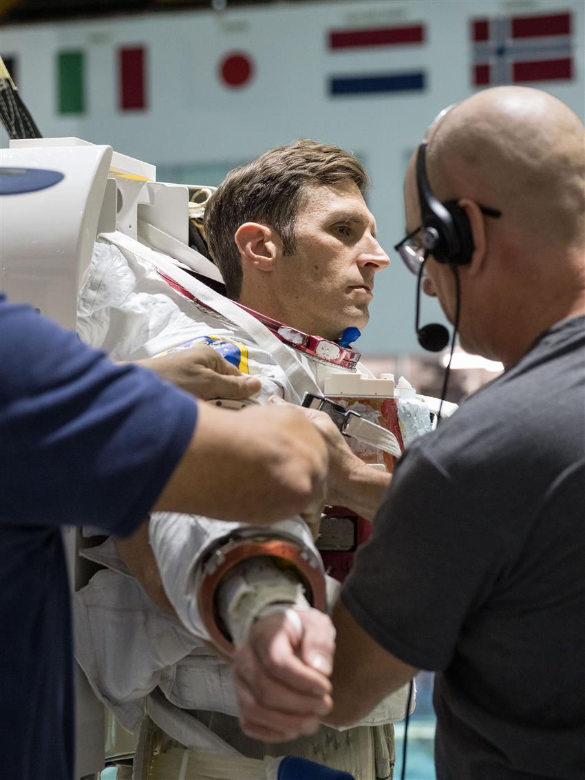 Un technicien aide Joshua à mettre sa combinaison spatiale.