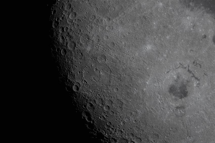An image of lunar surface craters, half in shadow. 