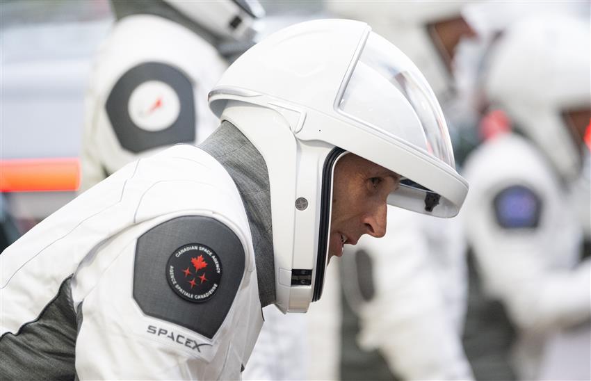 Joshua, dressed in his flight suit, leans forward to speak with his children. 