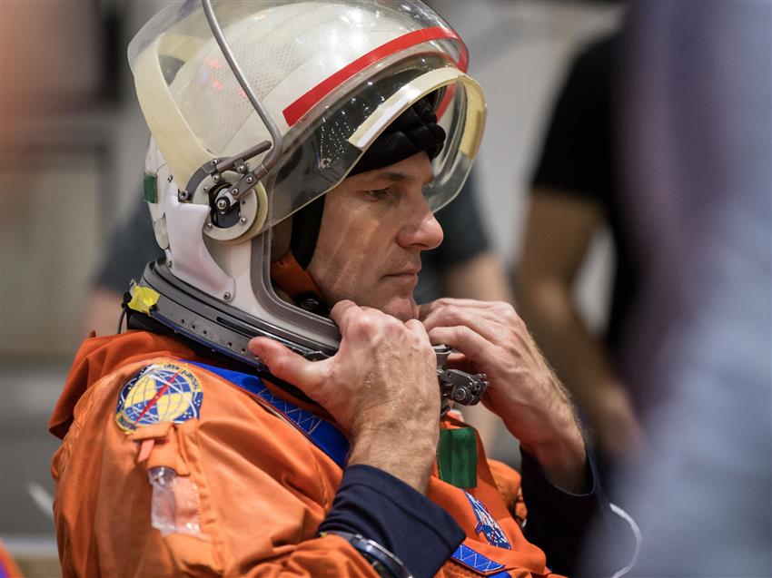 Close-up of Jeremy Hansen in a space suit. His helmet visor is turned up.