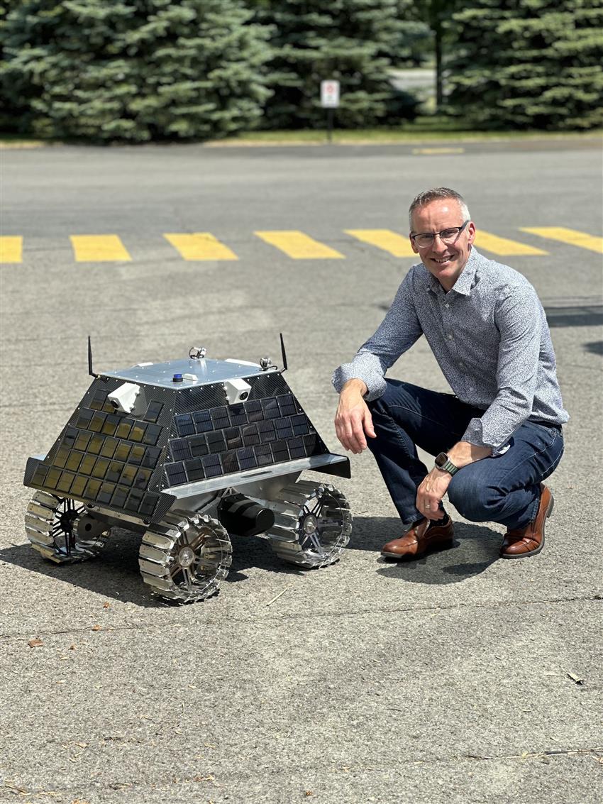 Gordon is posing with a lunar rover prototype.