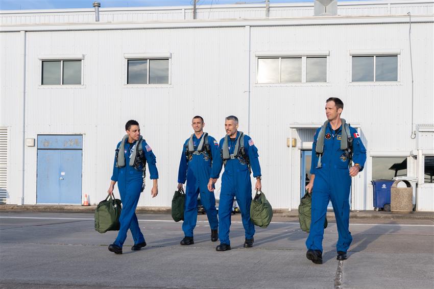 Jessica, Sergey, Luke and Josh walk in a line carrying duffel bags.
