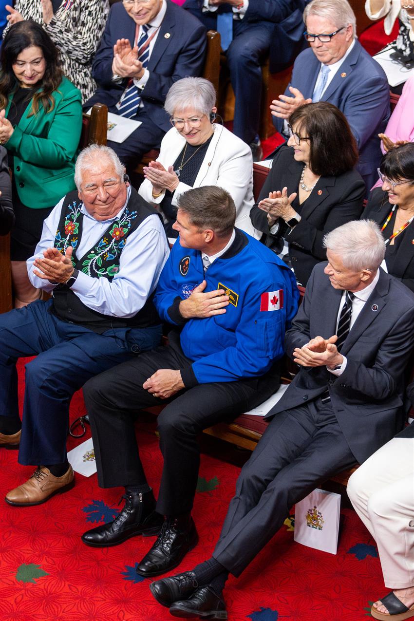 Jeremy holds his hand on his heart while being applauded by the people around him.