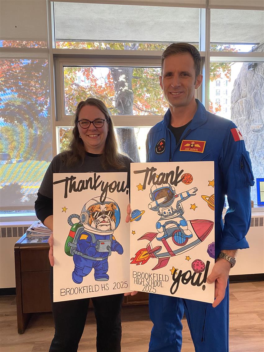 Une enseignante et Joshua montrent deux grandes cartes avec des dessins d'astronautes.