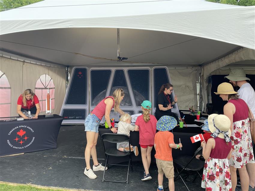Des familles réunies au kiosque de l'Agence spatiale canadienne à la fête du Canada à Ottawa