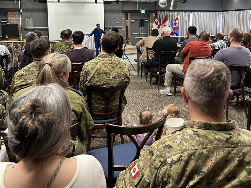 Jeremy stands in front of an audience, some people wearing military uniforms.