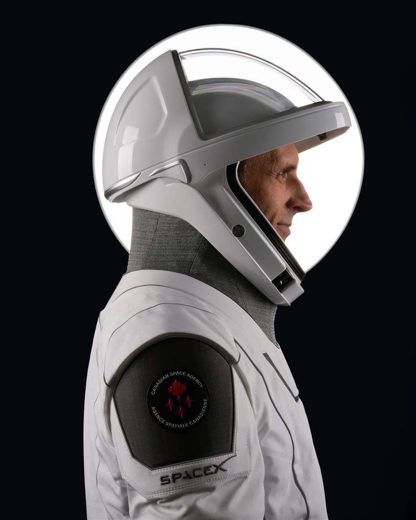 Joshua est de profil, un écusson du logo de l'Agence spatiale canadienne et le logo de SpaceX sur l'épaule.