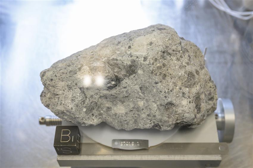 A grey and white Moon rock sample on a scale