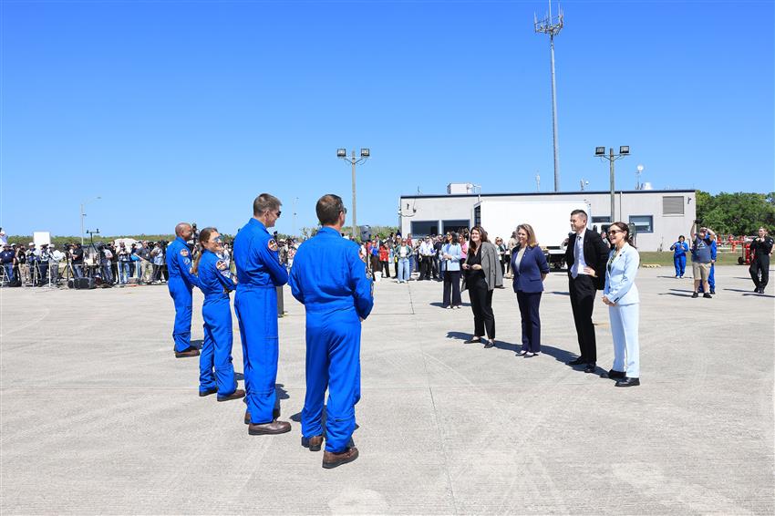The crew faces Lisa, Jared and two women at a distance, a large group of reporters in the background.