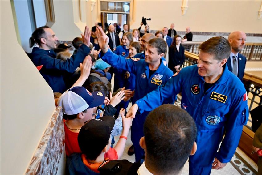 The astronauts line up to shake hands with students and teachers.