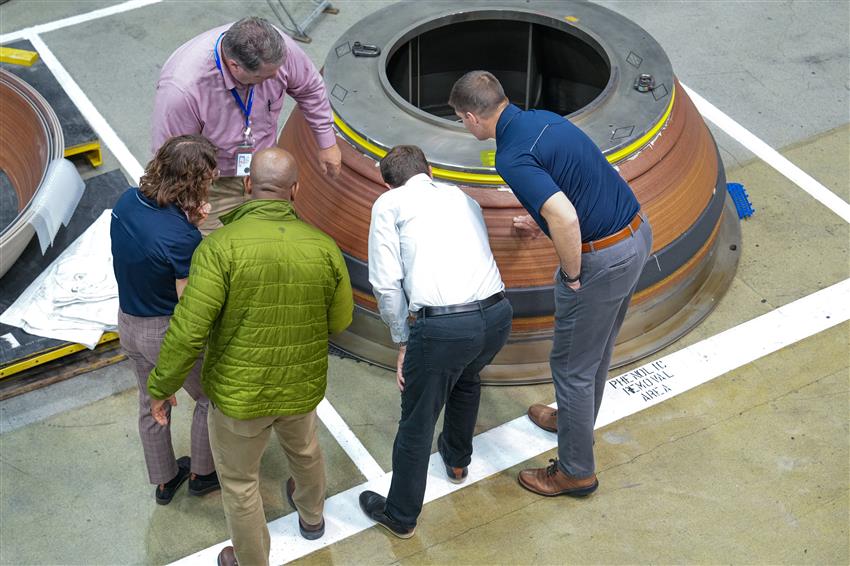 A group of people looking at a large metal object.