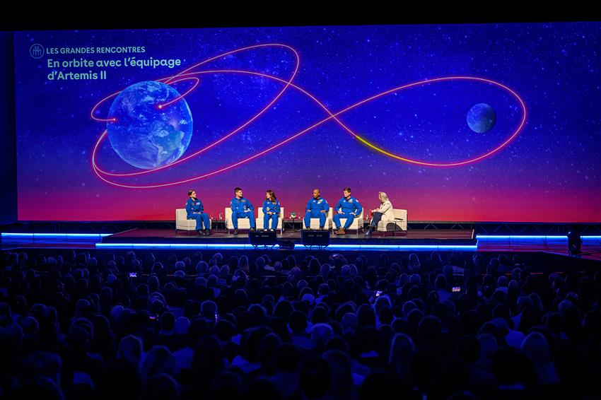 The five astronauts on stage with Isabelle, a giant screen behind them showing the trajectory of the mission.