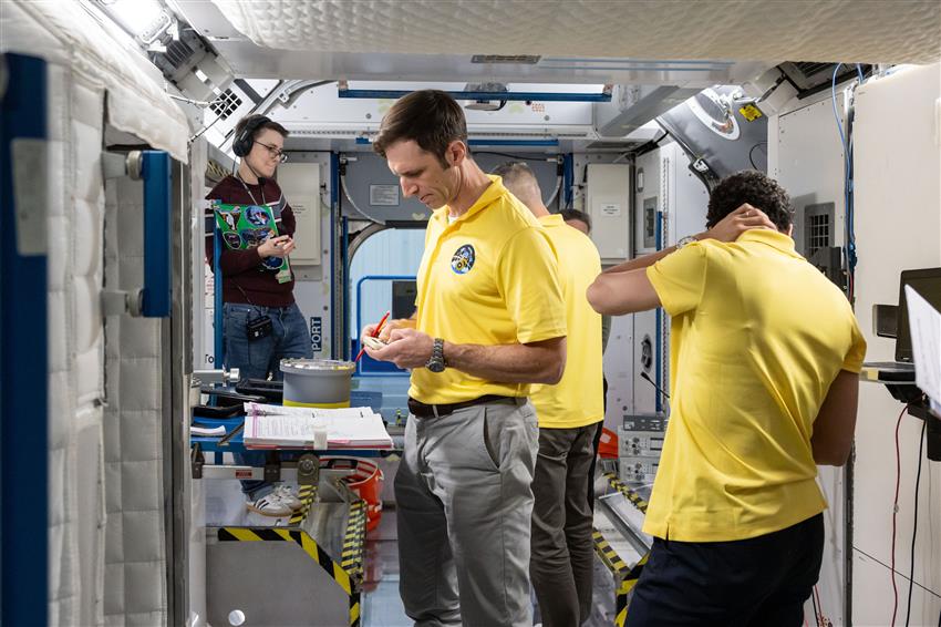 Joshua, avec une calculatrice à la main, et ses coéquipiers de Crew-13 dans une maquette de la SSI.
