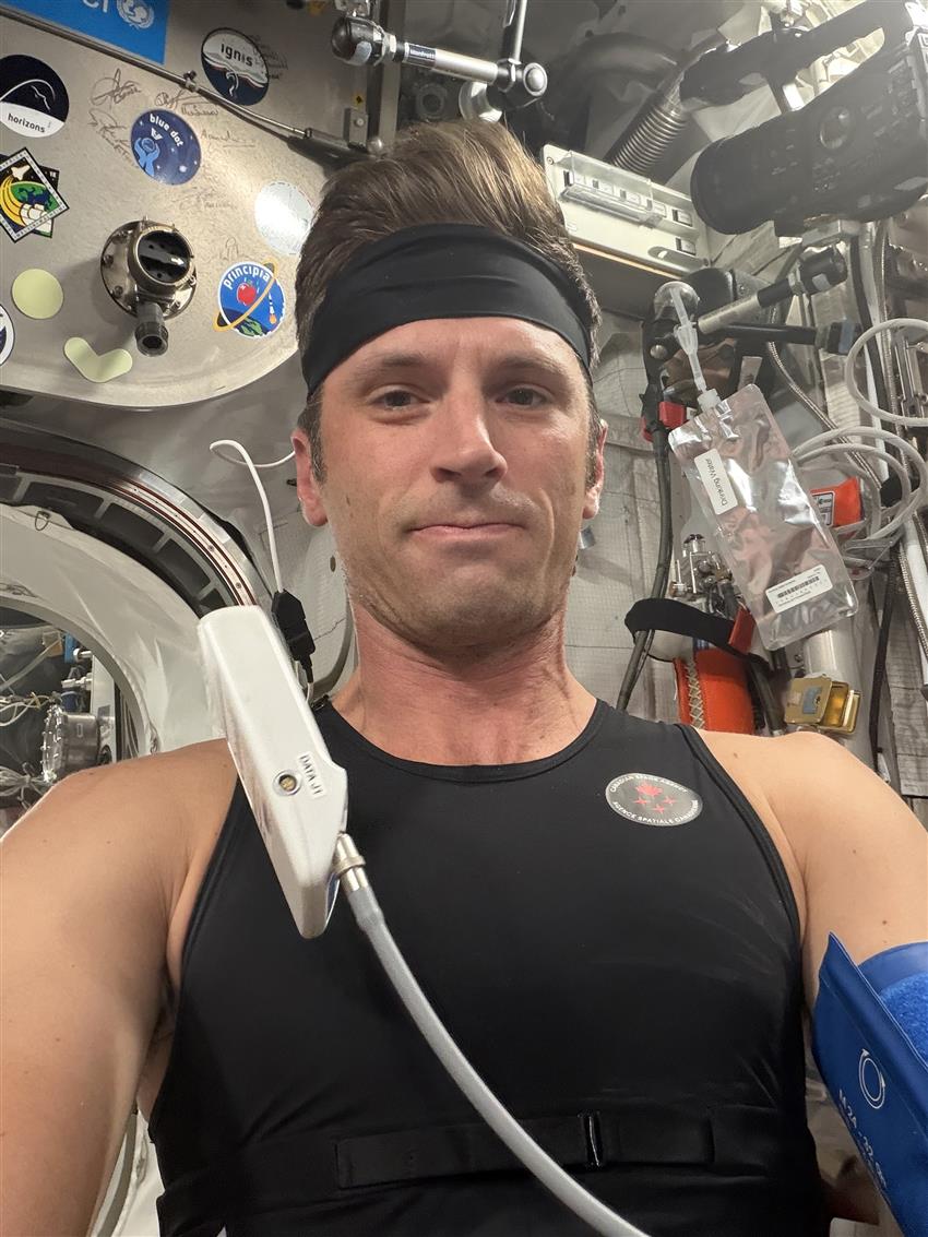 Joshua wears a form-fitting shirt and headband on the International Space Station. 
