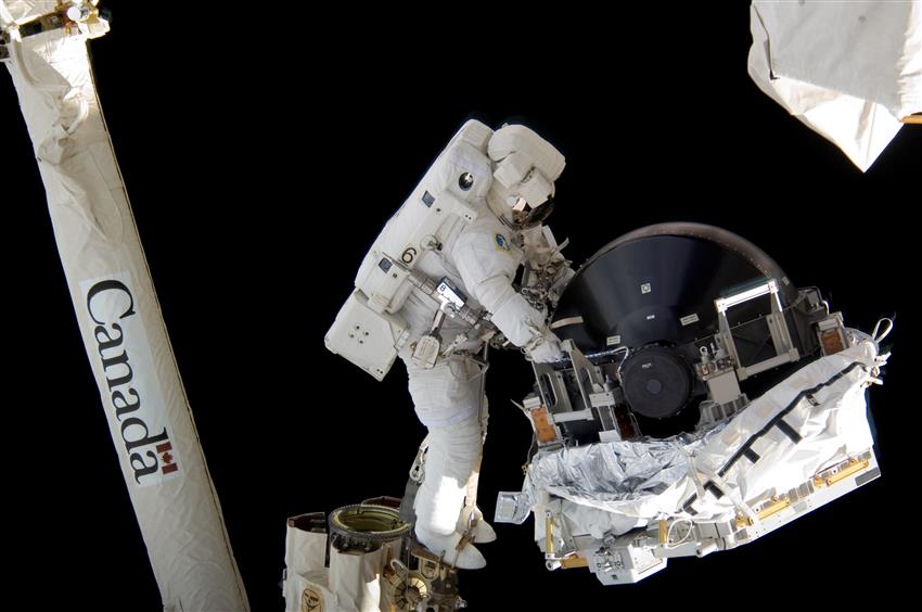 Anchored to the foot restraint on Canadarm2 during a spacewalk, astronaut Dave Williams is performing repairs