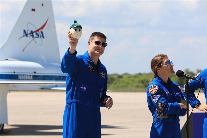 Jeremy holds a small plush Moon in the air. 