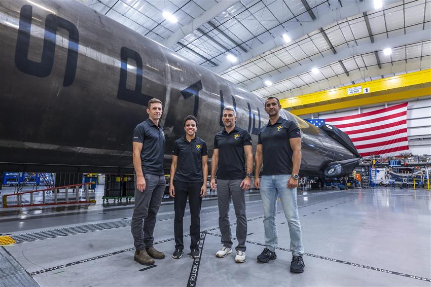 Joshua, Jessica, Luke, and Sergey pose in a hanger. 