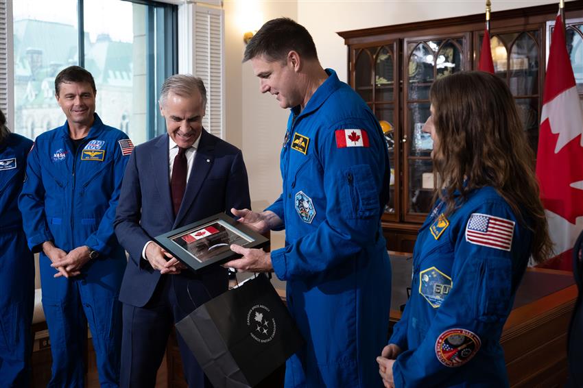 Jeremy presents a framed Canada flag to the Prime Minister, with Reid and Christina standing beside them.