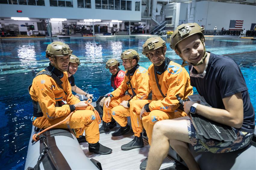 L'équipage de la mission Crew-13 et deux techniciens sont sur un radeau gonflable dans une grande piscine. 