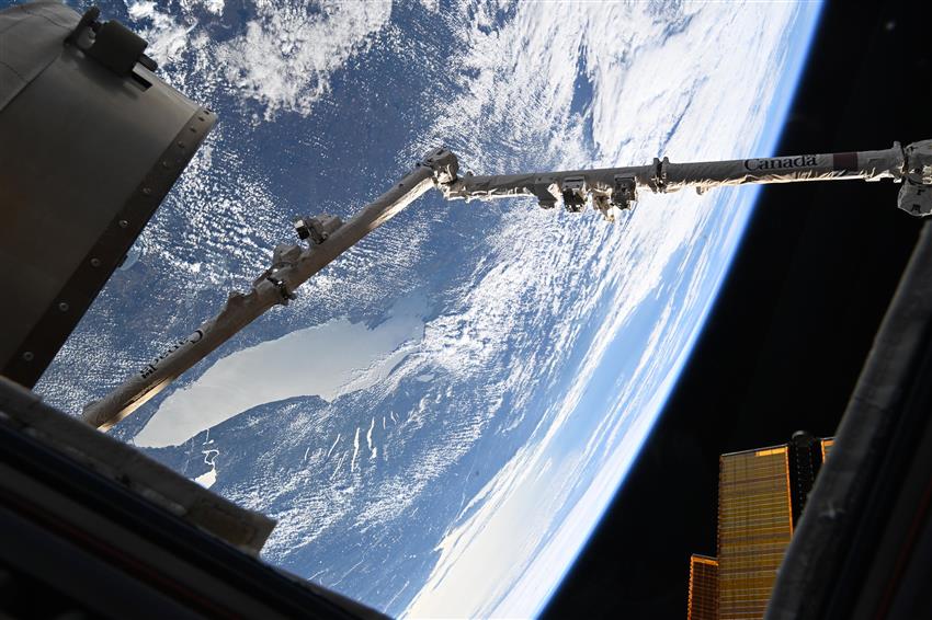 View of the Lake Ontario, with the Canadarm2 robotic arm visible in the foreground.